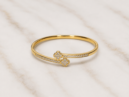 Evermore Double Clover Bracelet with gold finish and sparkling stones on a marble surface.