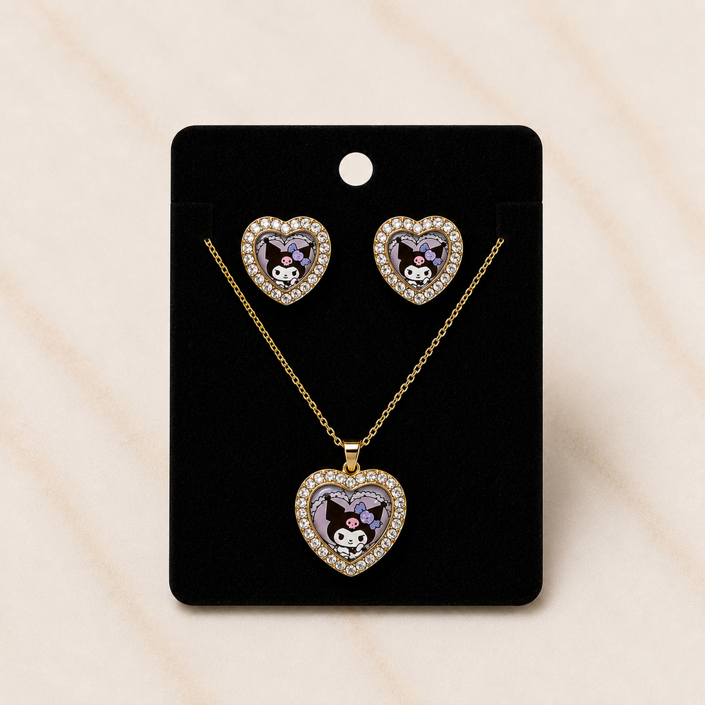 A heart-shaped jewelry set featuring a pendant necklace and matching stud earrings on a black display card. The heart pendants and studs are gold-tone with clear rhinestones around the edges and a central purple and white cartoon character motif.