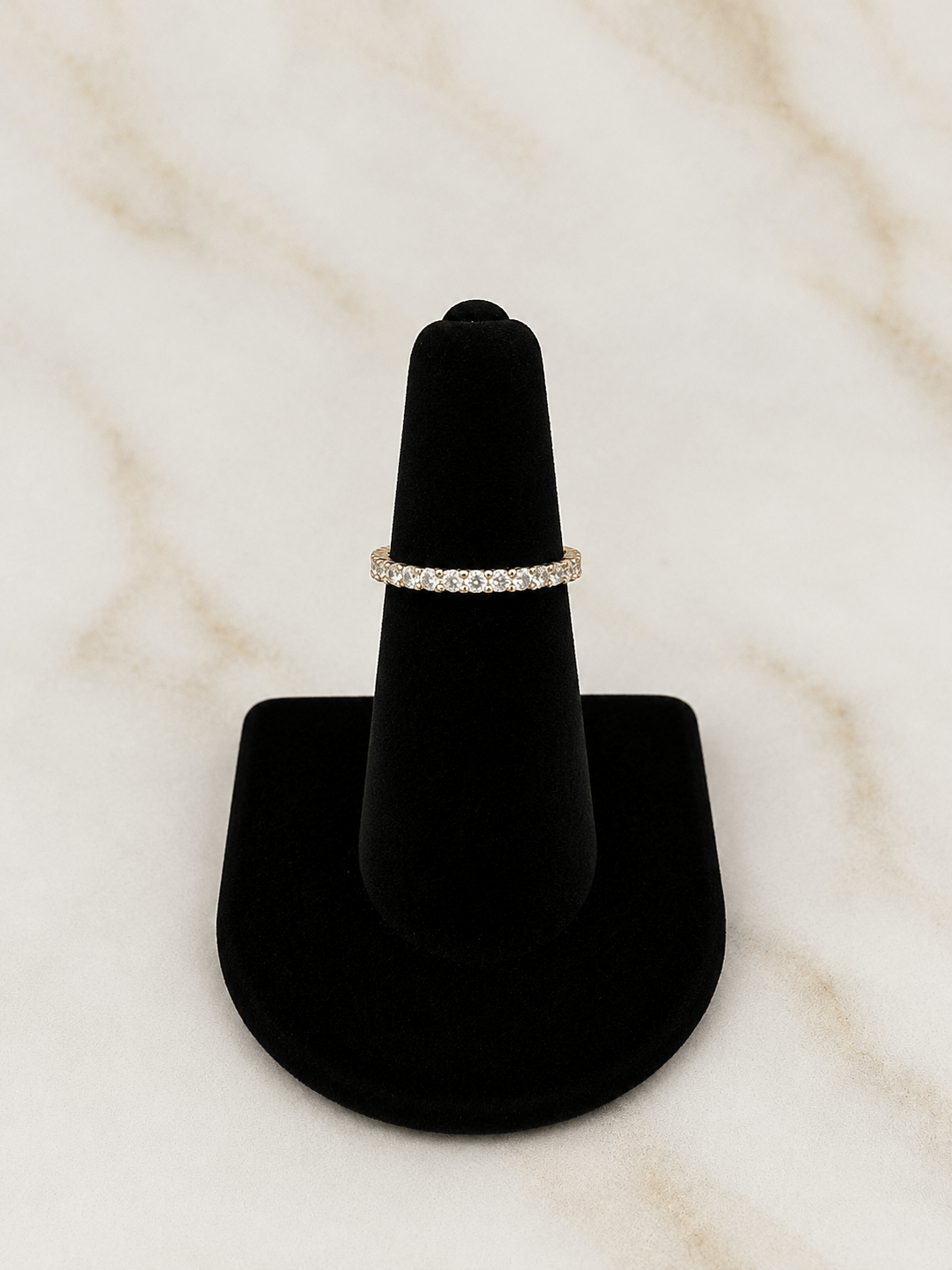 The Eternity Band Ring displayed on a black ring stand, showcasing its stunning cubic zirconia stones.