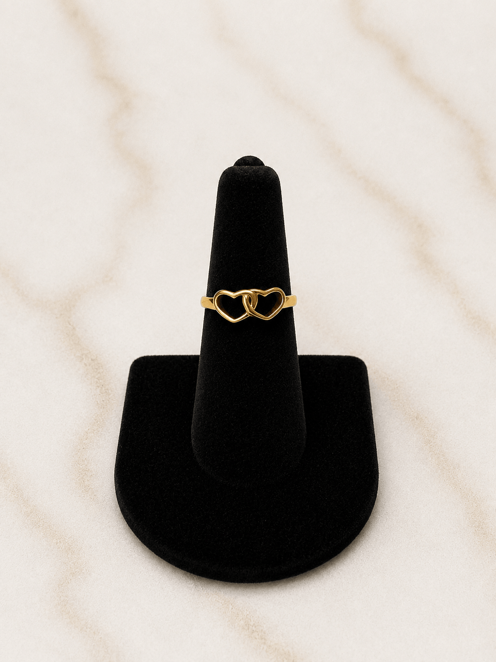The Golden Bond Ring featuring a double heart design on a black velvet ring holder.