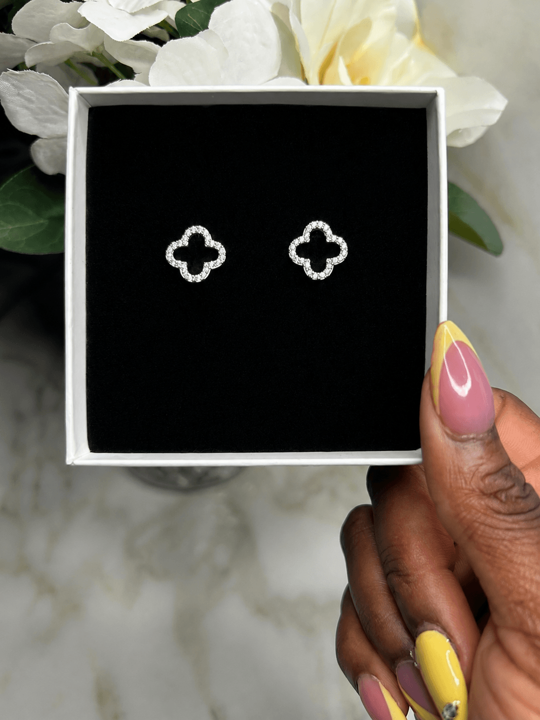 The Evermore Clover Earrings displayed in a box with elegant black lining.
