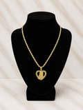 A gold heart-shaped pendant necklace with a textured, pave-like finish, displayed on a black velvet jewelry bust against a light marble-patterned background.