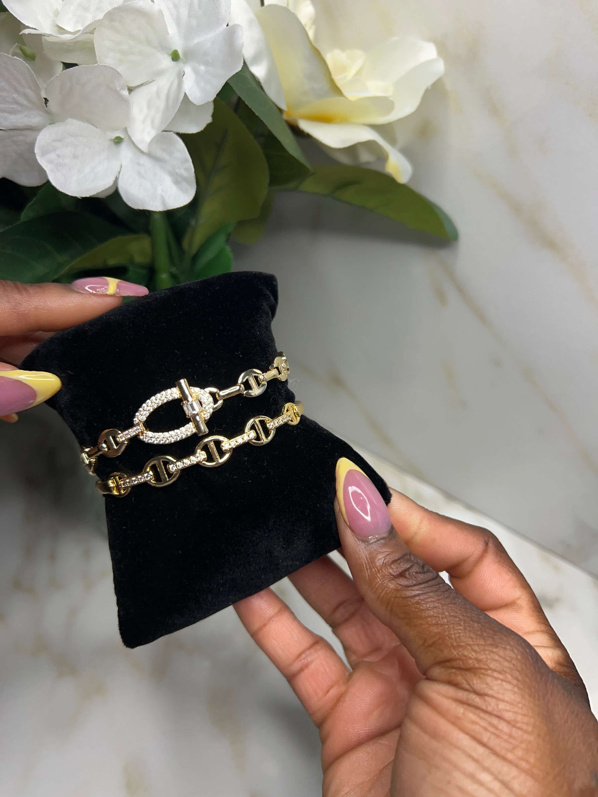 The Golden Reign Duo Stack featuring elegant gold-tone chain and circle bracelets on a black velvet display.