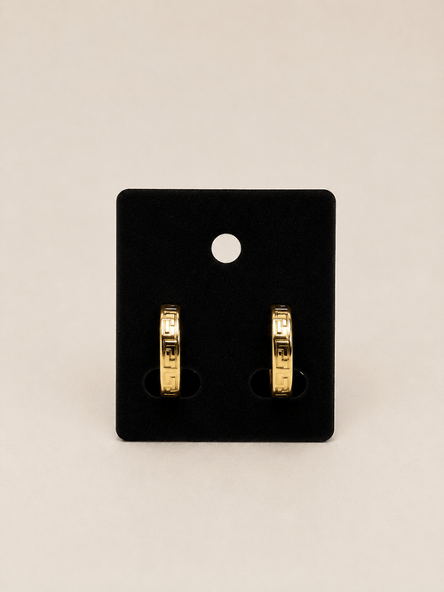 A pair of gold hoop earrings displayed on a black rectangular jewelry card against a light beige background.